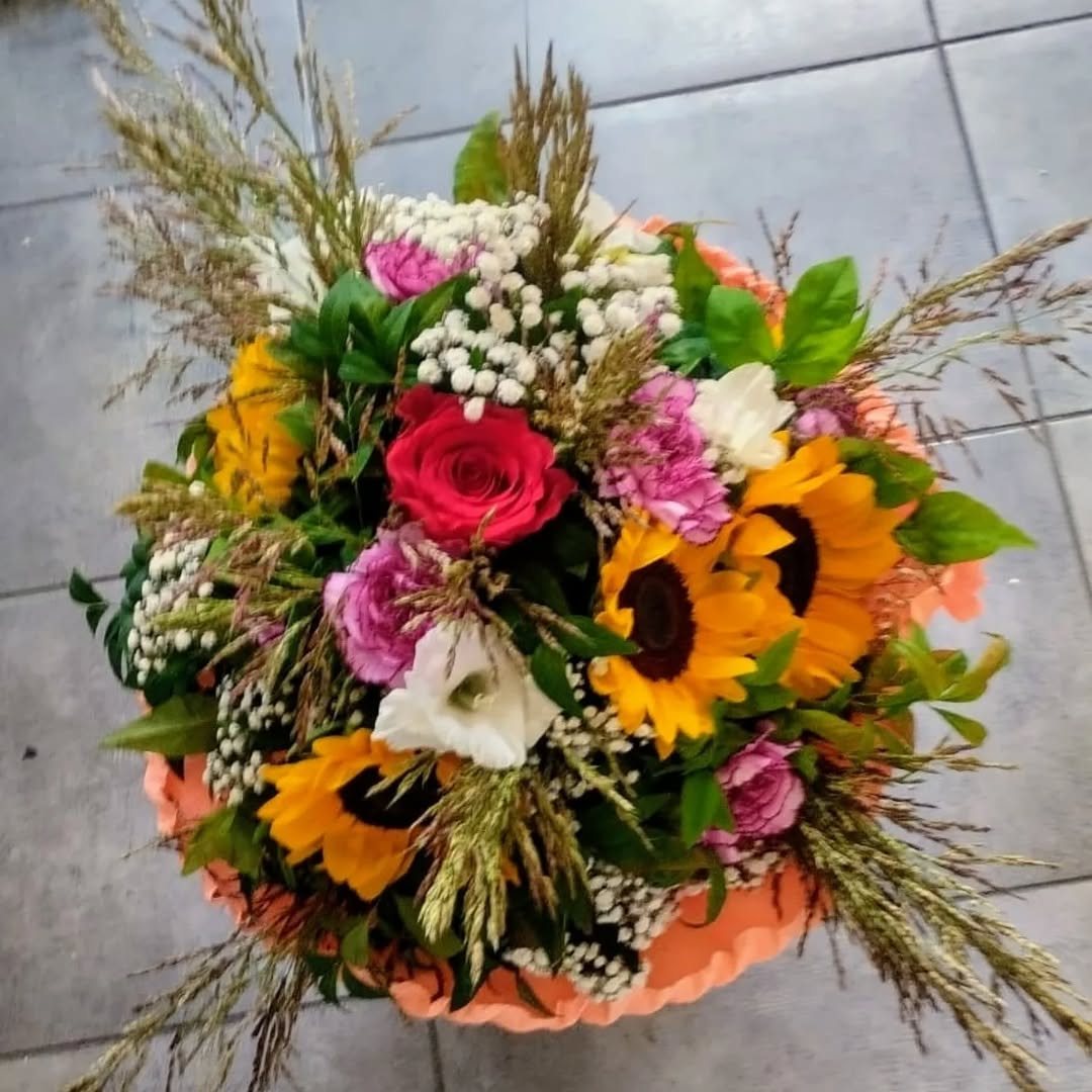 Composizione con girasoli, rose e garofani in carta crespa corallo