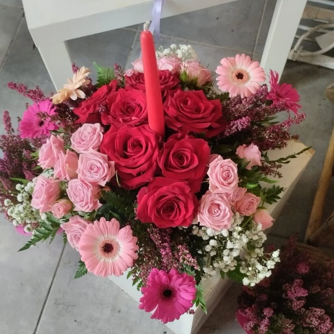 Centrotavola con rose rosse e rosa, gerbere e candela