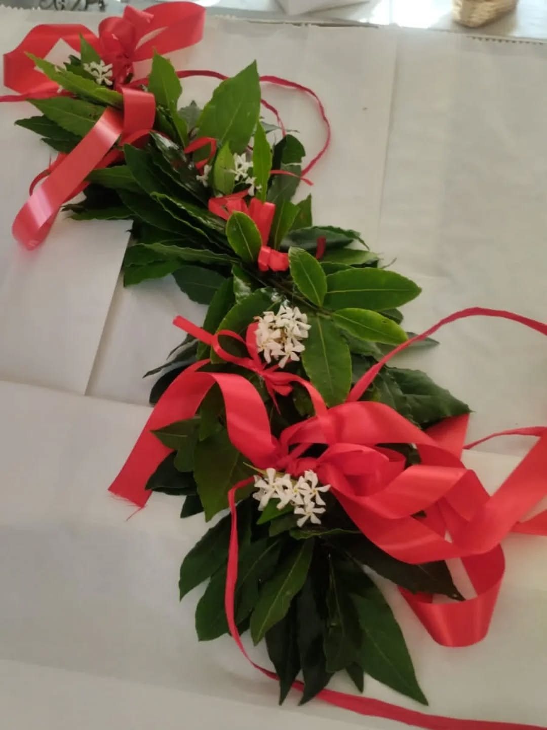 Corona d'alloro con nastri rossi e fiori bianchi